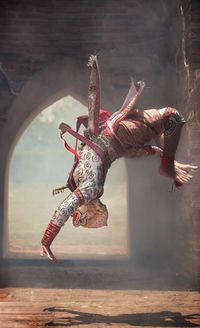 Side view of man in costume jumping on footpath