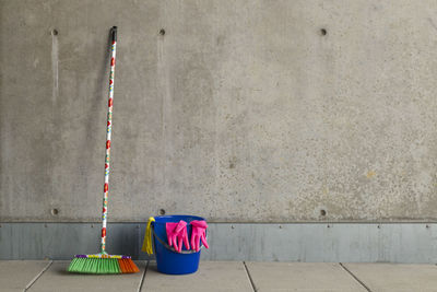 Multi colored broom with bucket on floor against wall