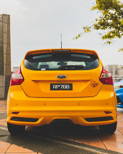 Yellow car in city against sky