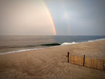 Scenic view of sea against rainbow in sky