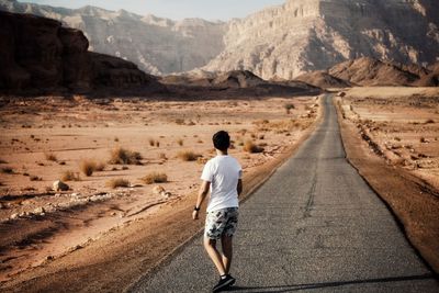 Rear view of man walking on road