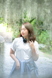 Young woman looking away while standing outdoors