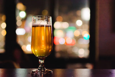 Close-up of beer in glass on table against window in bar