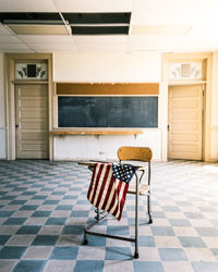 American flag on table by empty chair over tiled floor