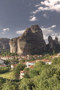 Rock formations by buildings in city against sky