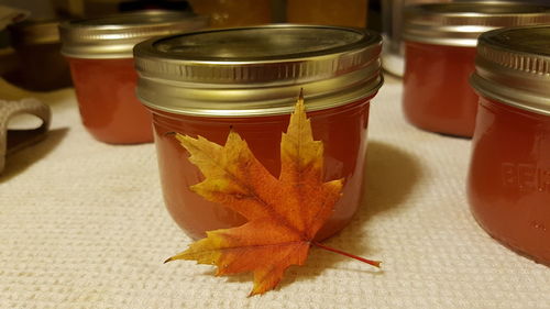 Close-up of maple leaf by jam in jars on table