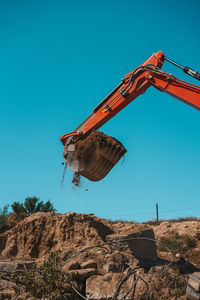 Low angle view of crane against clear blue sky