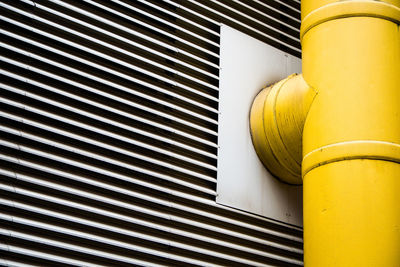 Low angle view of yellow pipe against wall