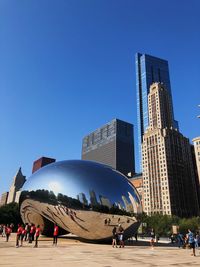 People on modern building against clear blue sky