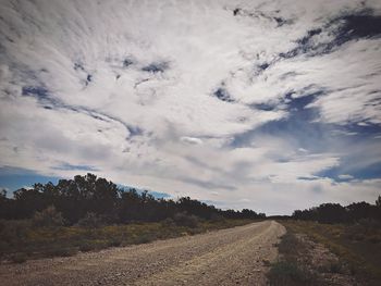 Surface level of country road against cloudy sky