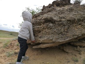 Side view of boy standing on rock