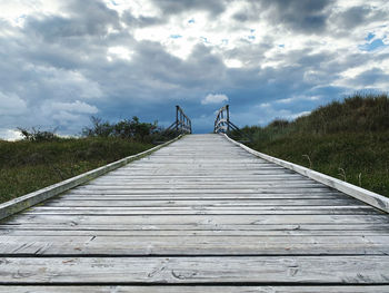 Surface level of wooden footbridge against sky