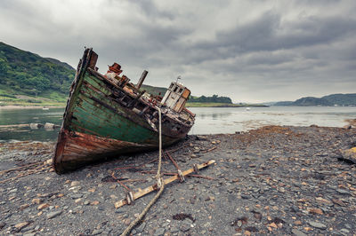 Abandoned ship on beach against sky