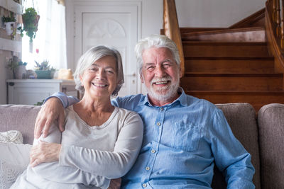 Portrait of smiling couple sitting on sofa at home