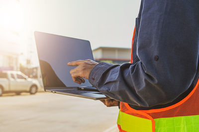 Midsection of woman using laptop at table