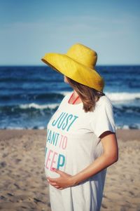 Pregnant in hat woman standing on beach