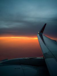 Airplane flying over cloudscape during sunset