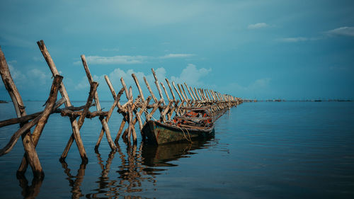 Abandoned boat moored in sea against sky