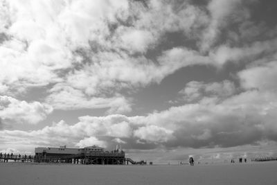 View of calm beach against cloudy sky