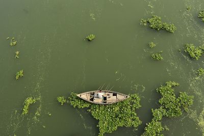 High angle view of boat floating on river and fishing by fishing rod