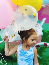 Cute girl with balloons standing outdoors
