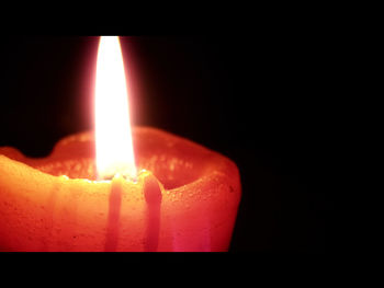 Close-up of lit candle in dark room