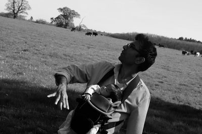 Tilt shot of man with baby in carrier standing on field