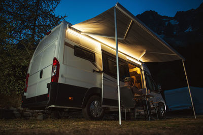 Low angle view of man sitting by camper van