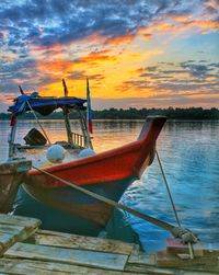 Boat moored on sea against sky during sunset