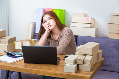 Portrait of young woman using phone while sitting on wall