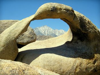 Mobius arch rock formation against clear blue sky framing mountain range