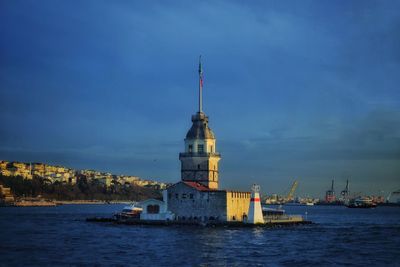 Sailboat on sea by buildings against sky