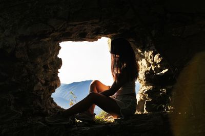 Teenage girl sitting on rock in cave