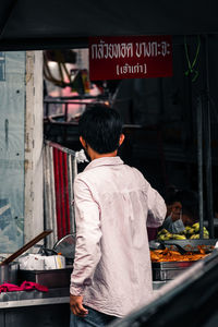 Rear view of man standing at market