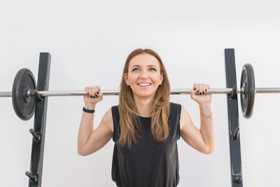 Portrait of smiling young woman standing against white background