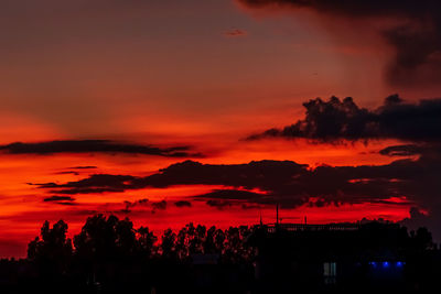 Silhouette trees against dramatic sky during sunset