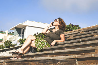 Woman sitting on staircase against sky