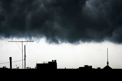 Low angle view of silhouette building against cloudy sky