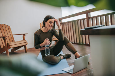 Woman using phone while sitting on table