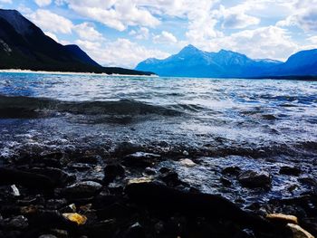 Scenic view of sea by snowcapped mountains against sky