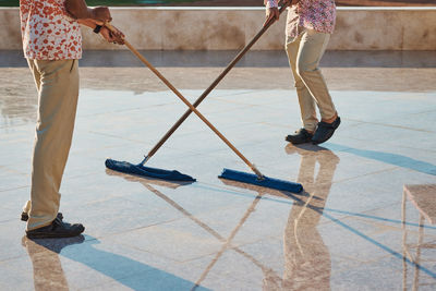 Low section of people cleaning tiled floor