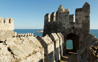 Old ruins of fortress by sea against clear blue sky