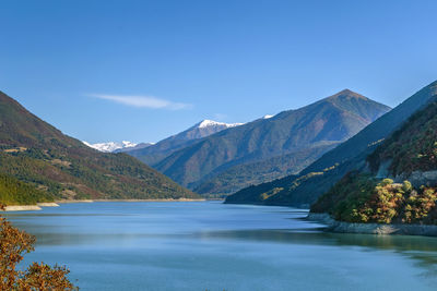 Scenic view of lake and mountains against blue sky