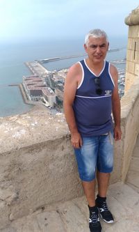 Portrait of a smiling young man standing against sea