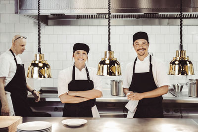 Portrait of happy chefs standing at commercial kitchen counter