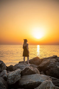 Man looking at sea against sky during sunset