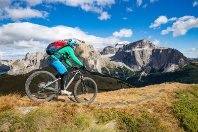 Man riding bicycle on mountain road against sky