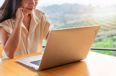 Midsection of woman using laptop at table