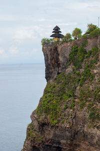 Rock formation by sea against sky