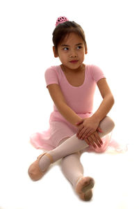 Girl looking away while sitting against white background